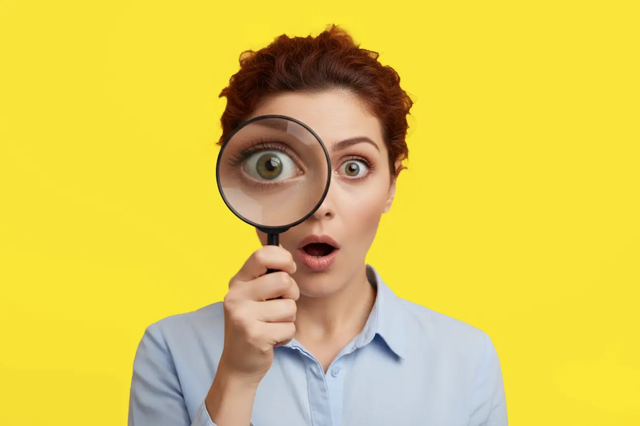 Femme utilisant une loupe pour symboliser la précision en compréhension écrite en anglais professionnel (TOEIC Reading).